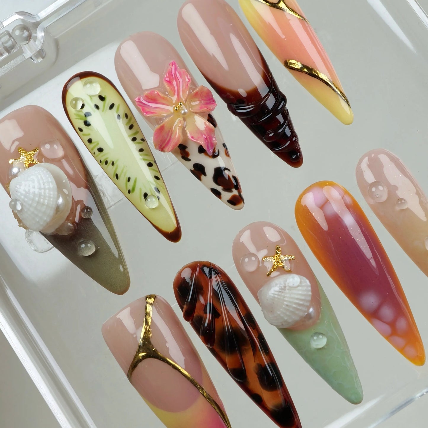 Tropical-themed summer nails showcasing a mix of designs like flowers, animal print, and seaside elements.