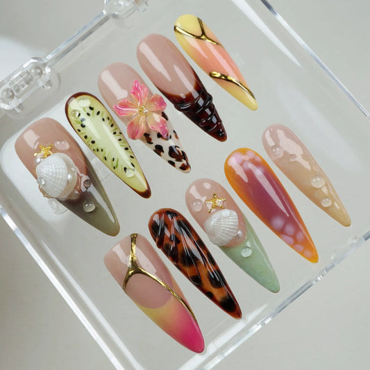 A set of vibrant press-on summer nails featuring kiwi art, leopard print, shells, and sunset ombré tones.
