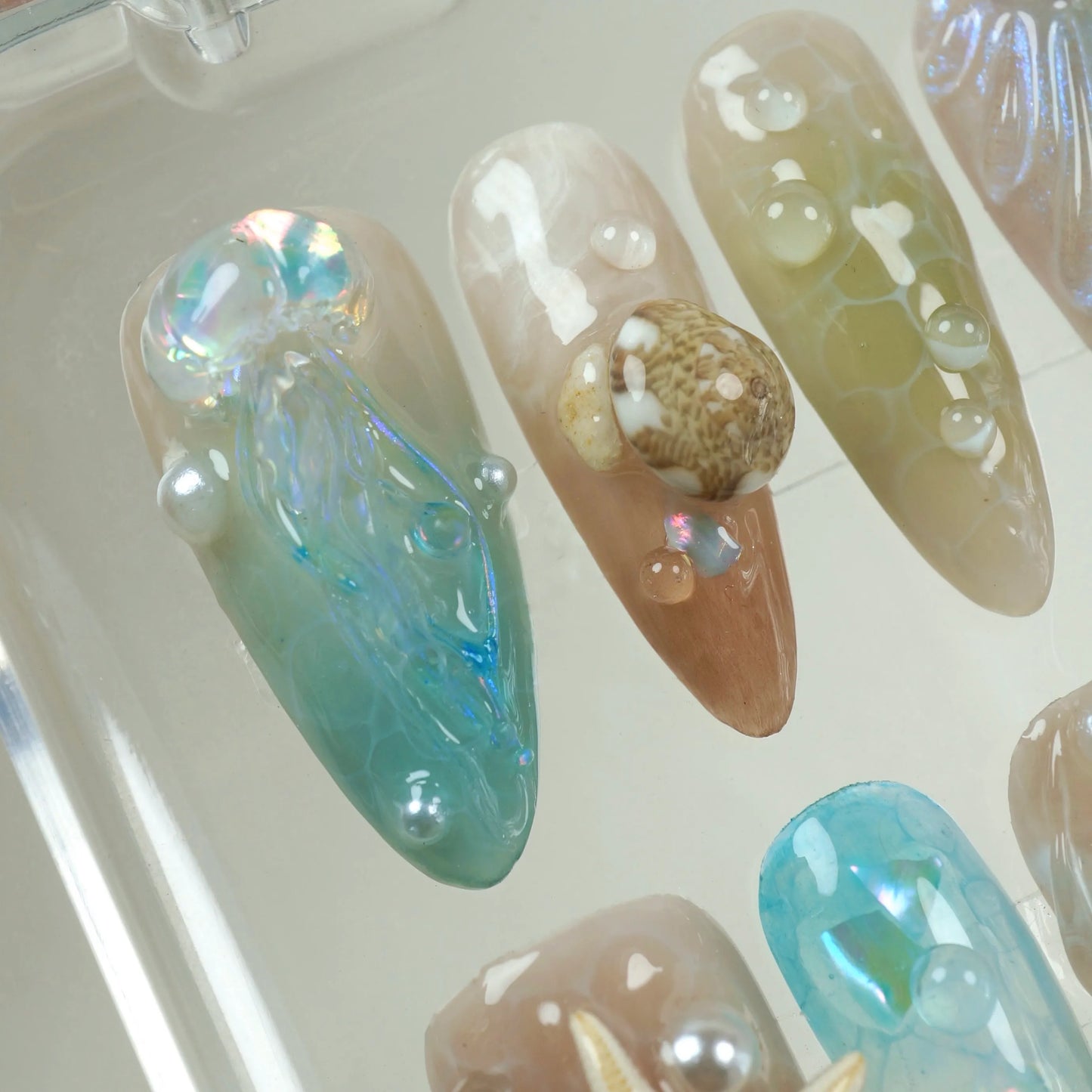 Mermaid-core summer nails with sea-inspired shimmer, bubbles, and natural shell embellishments.