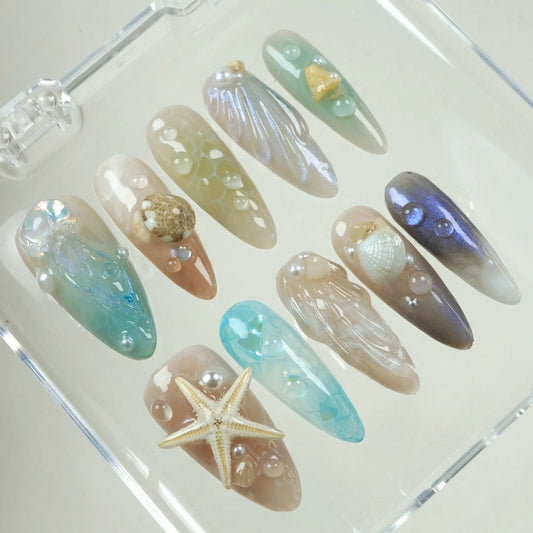 Beach-themed press-on summer nails featuring marine elements like shells, starfish, and water droplet effects.