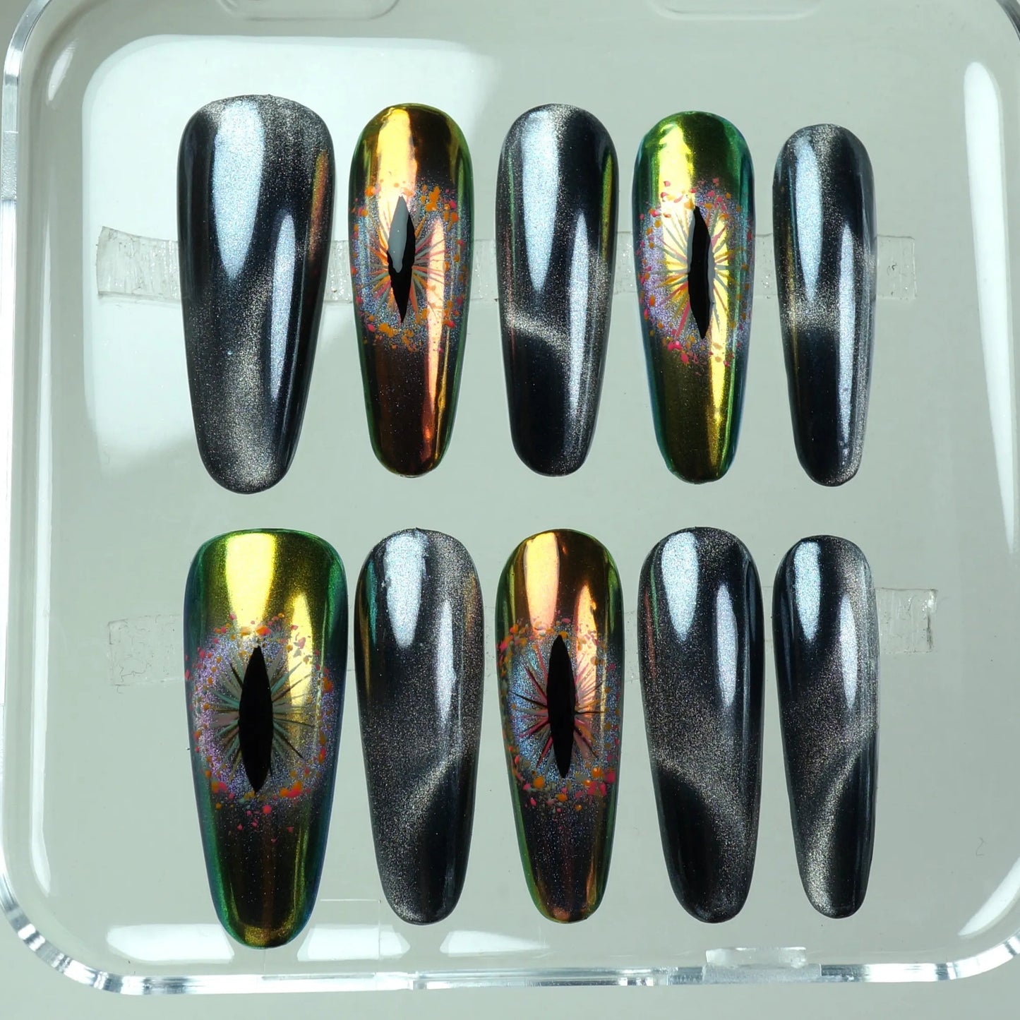 Mystical press-on nails from Donailsart with glowing eye motifs and sleek, metallic gradients