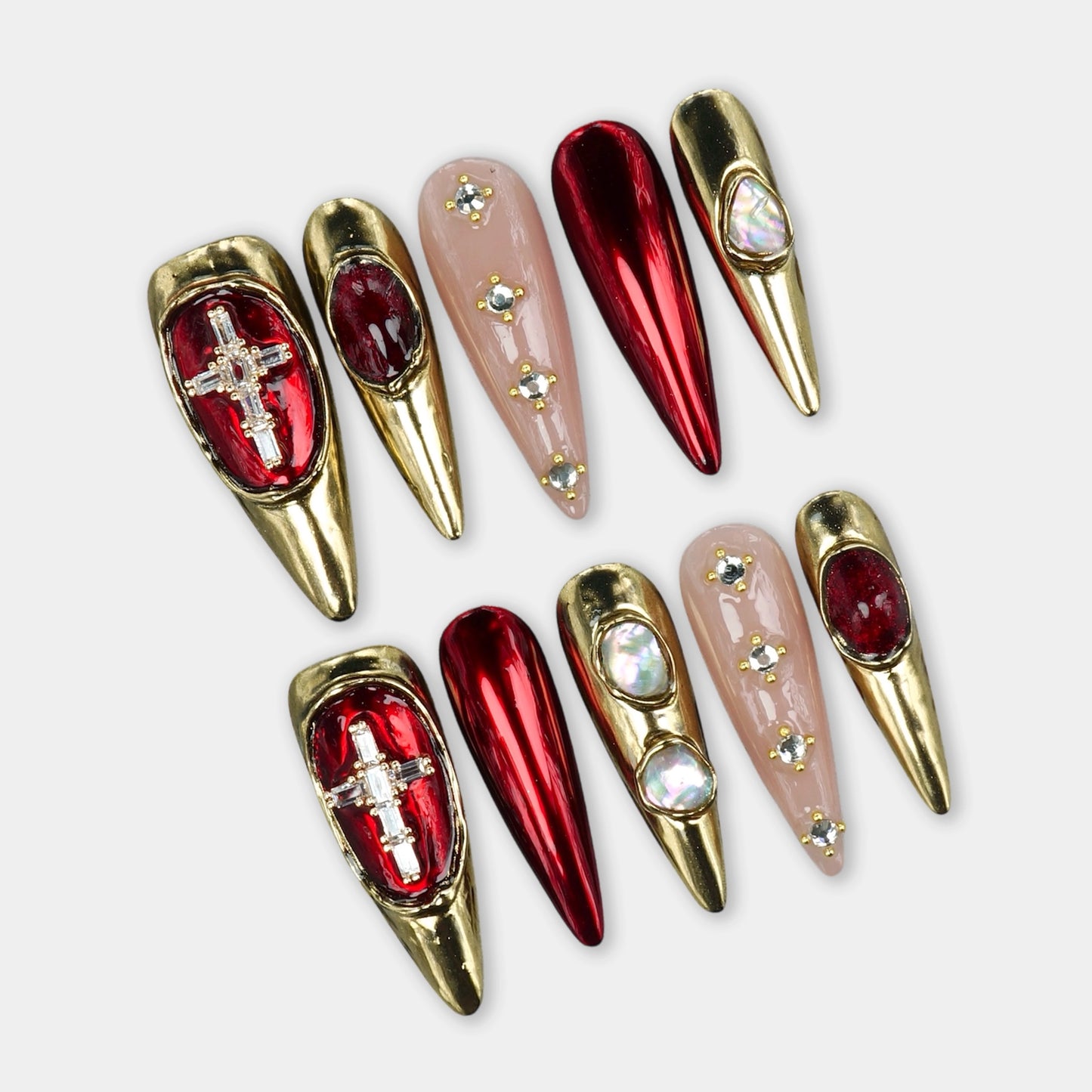 Luxury press-on nails with chrome red tips, gold metallic frames, and gemstone embellishments by Donailsart