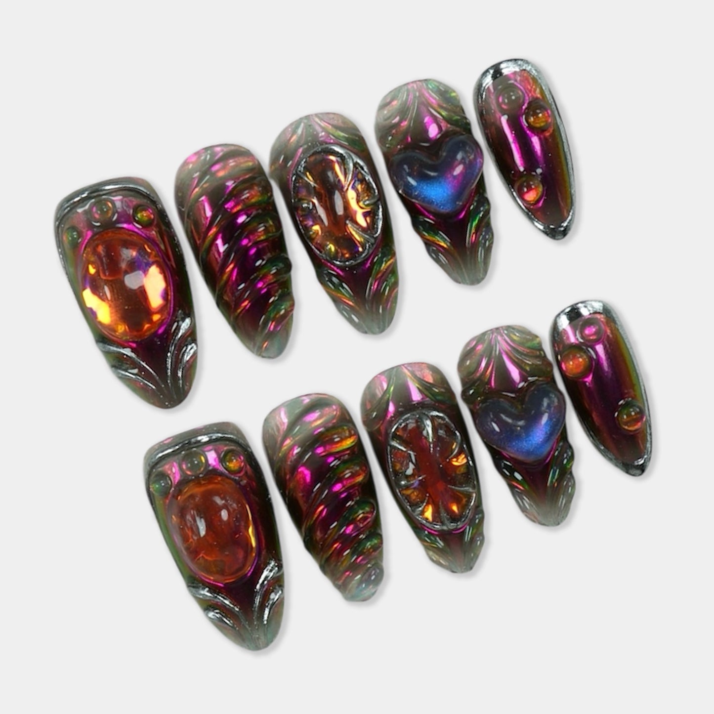 Chrome press-on nails from Donailsart with sculpted 3D shapes, glowing amber gems, and galaxy heart accents