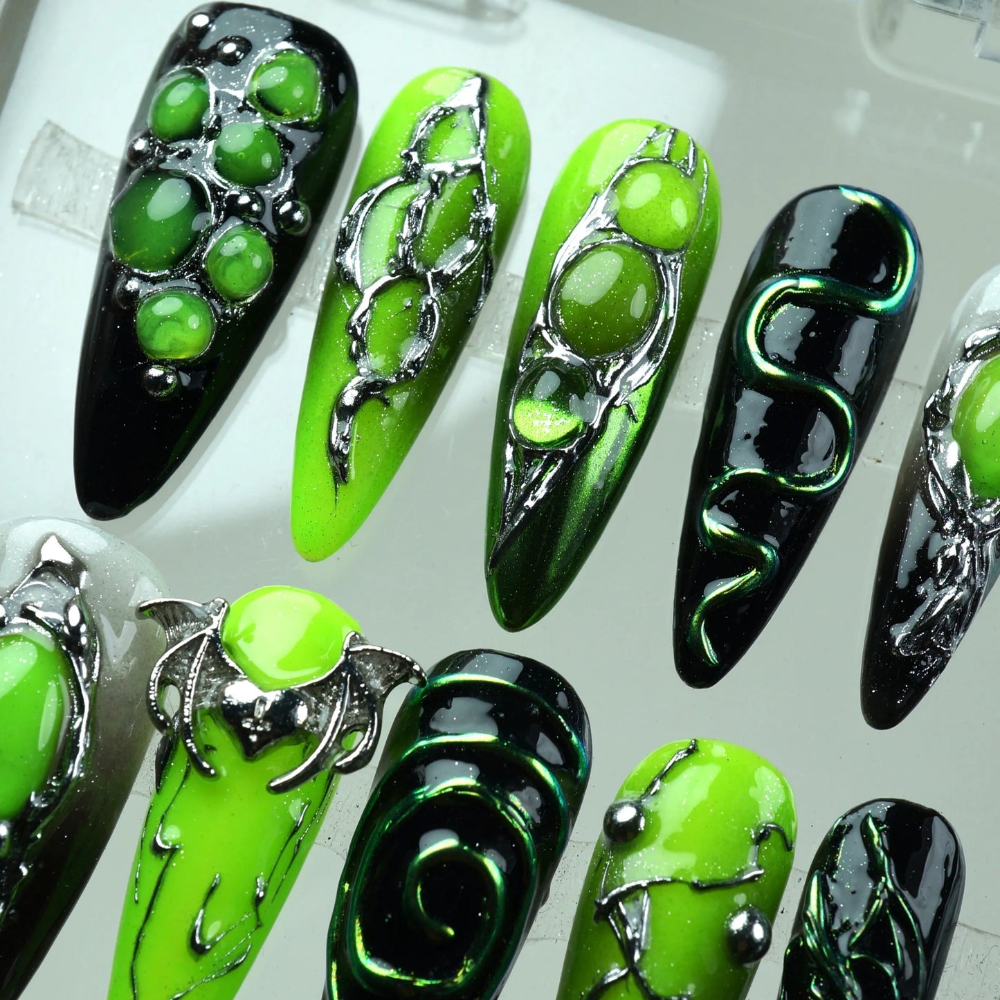 Press-on nails with neon green and black base, metallic alien-inspired details, and chrome 3D embellishments by Donailsart