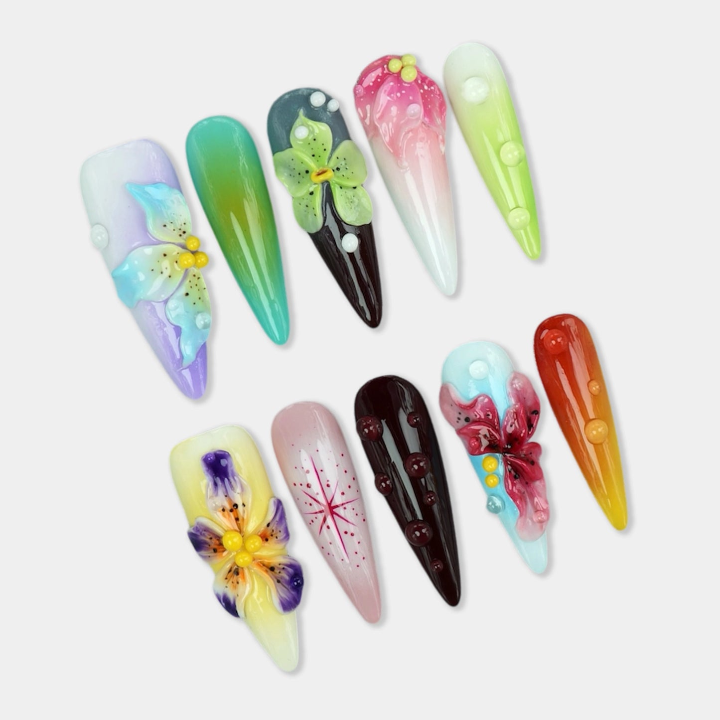 Multicolor press-on nails with 3D flowers, water droplets, and gradient effects in pastel and jewel tones from Donailsart