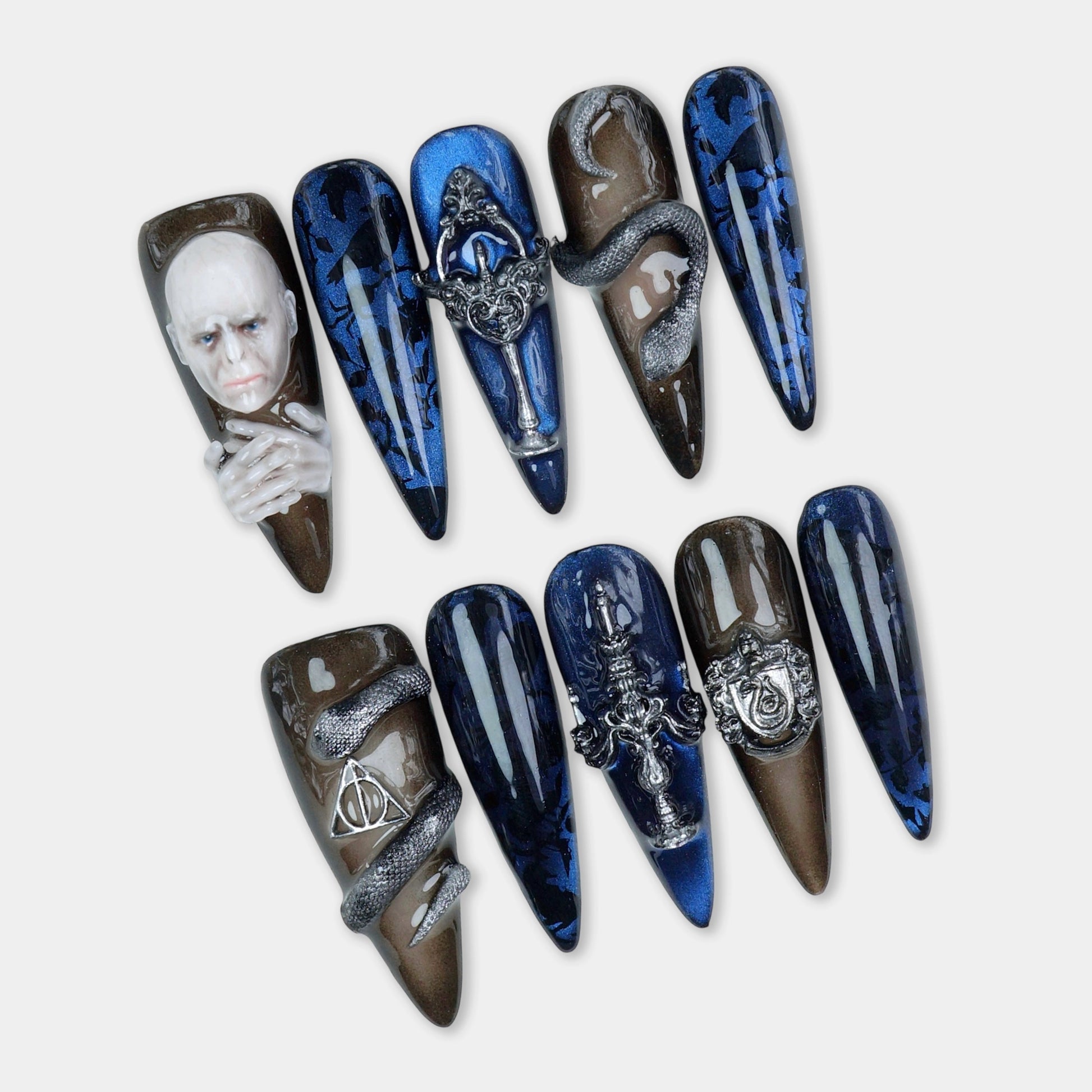Dark fantasy-themed press-on nails with snake, gothic metal charms, and a 3D villain face design