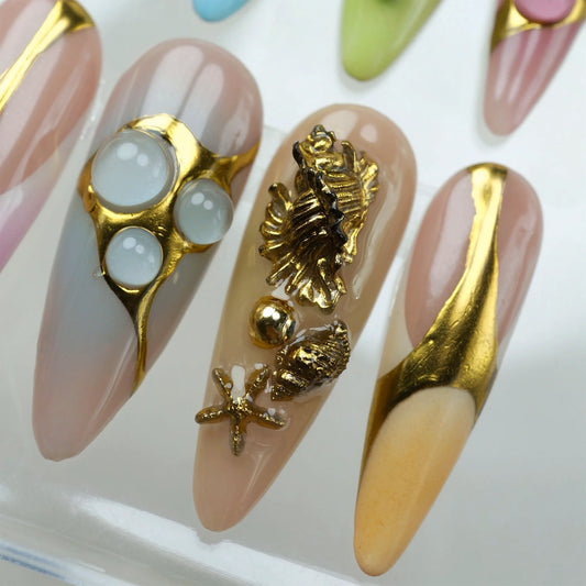 Luxury press-on nails by Donailsart featuring gold marine charms, seahorses, and seashells on gradient pastel bases