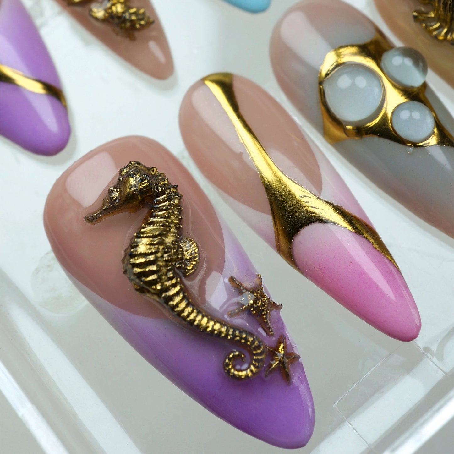 Colorful press-on nails from Donailsart with beach-themed gold accents, including lobsters, starfish, and bubbles on ombré nails
