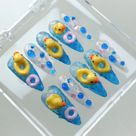 Summer-themed funny nails with rubber duck miniatures and sparkling pool-inspired designs