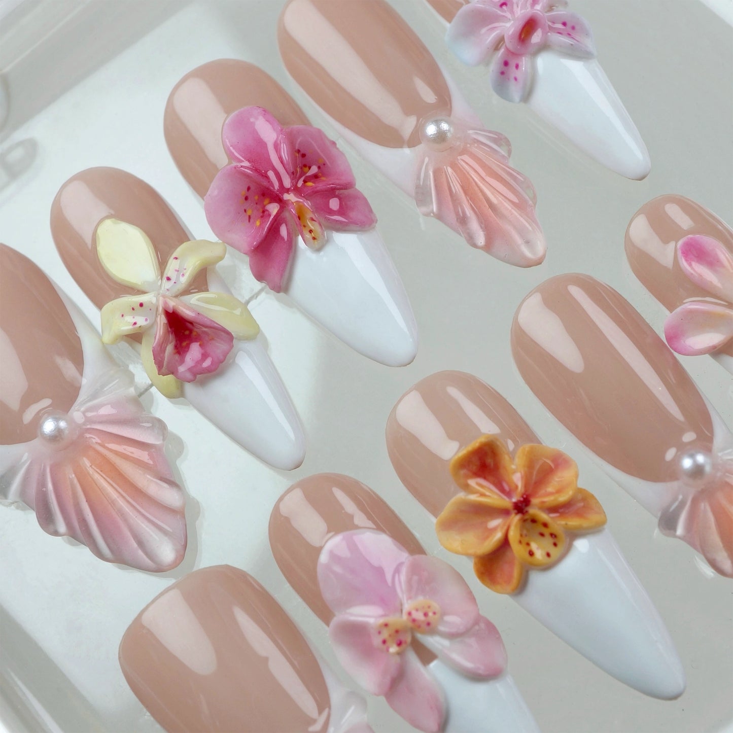 Flower nails with pastel 3D blossoms, white tips, and seashell-inspired accents on a nude base