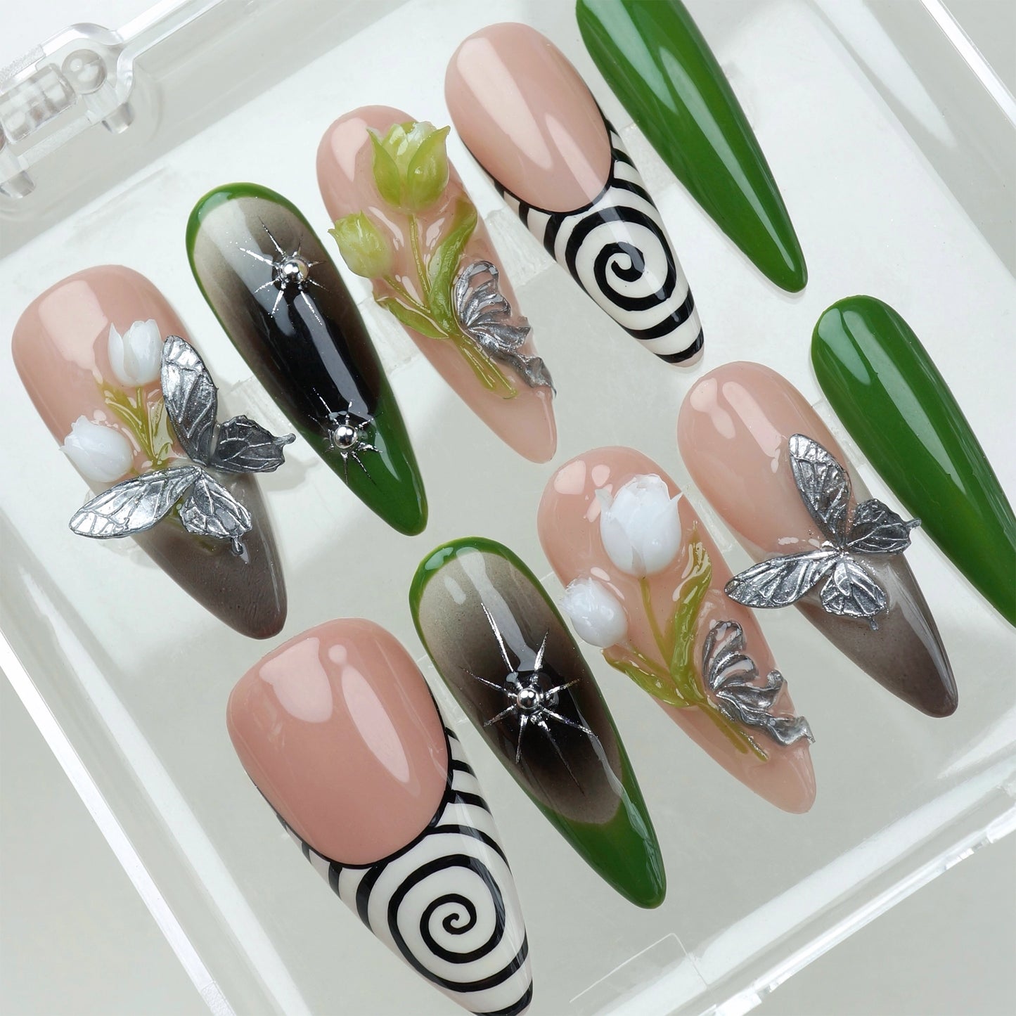 Set of flower nails with 3D white blossoms, silver butterflies, green ombré accents, and black-and-white spiral designs on nude base press-ons