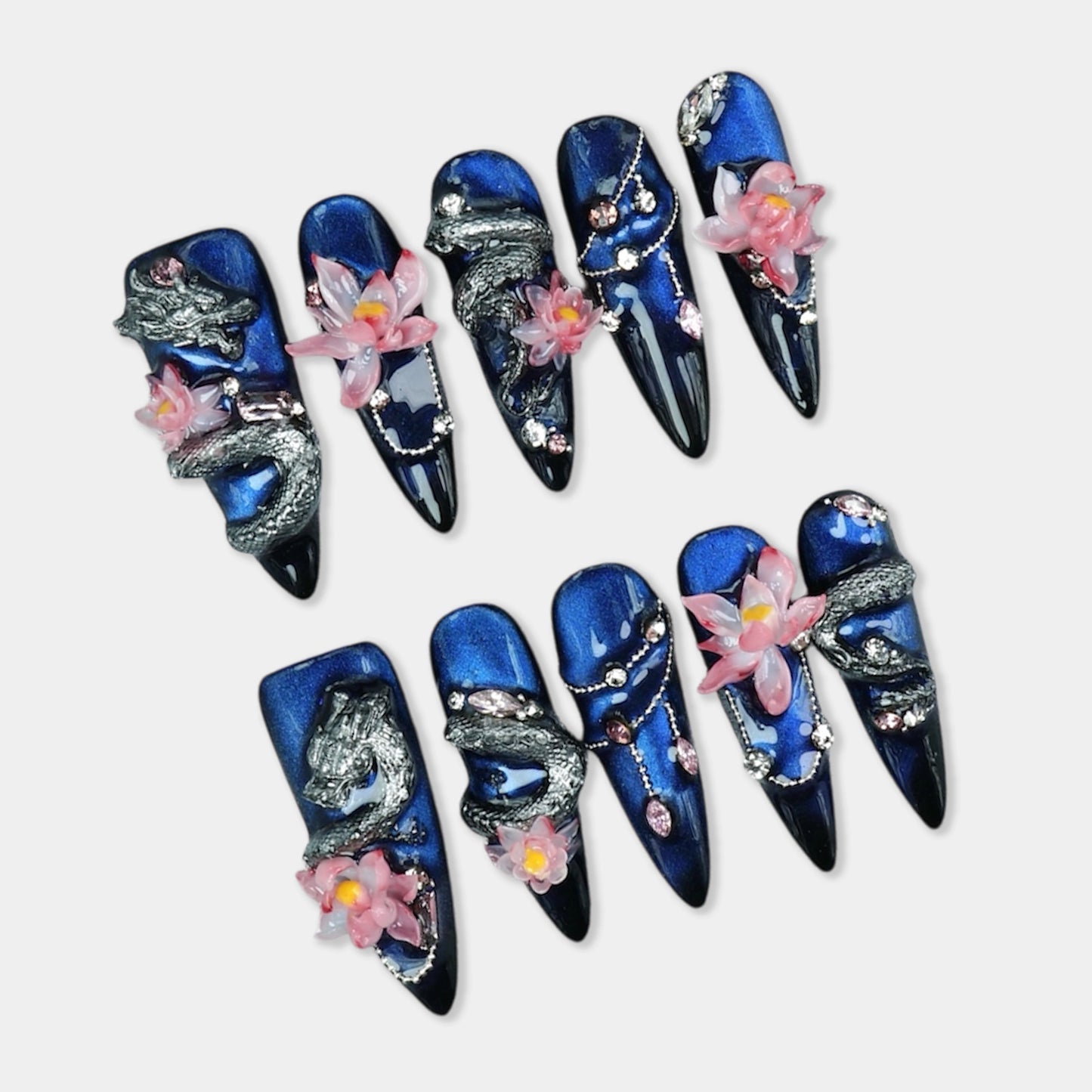 Sculptural nails art with silver dragon designs, pink lotus flowers, and deep blue shimmer base by Donailsart