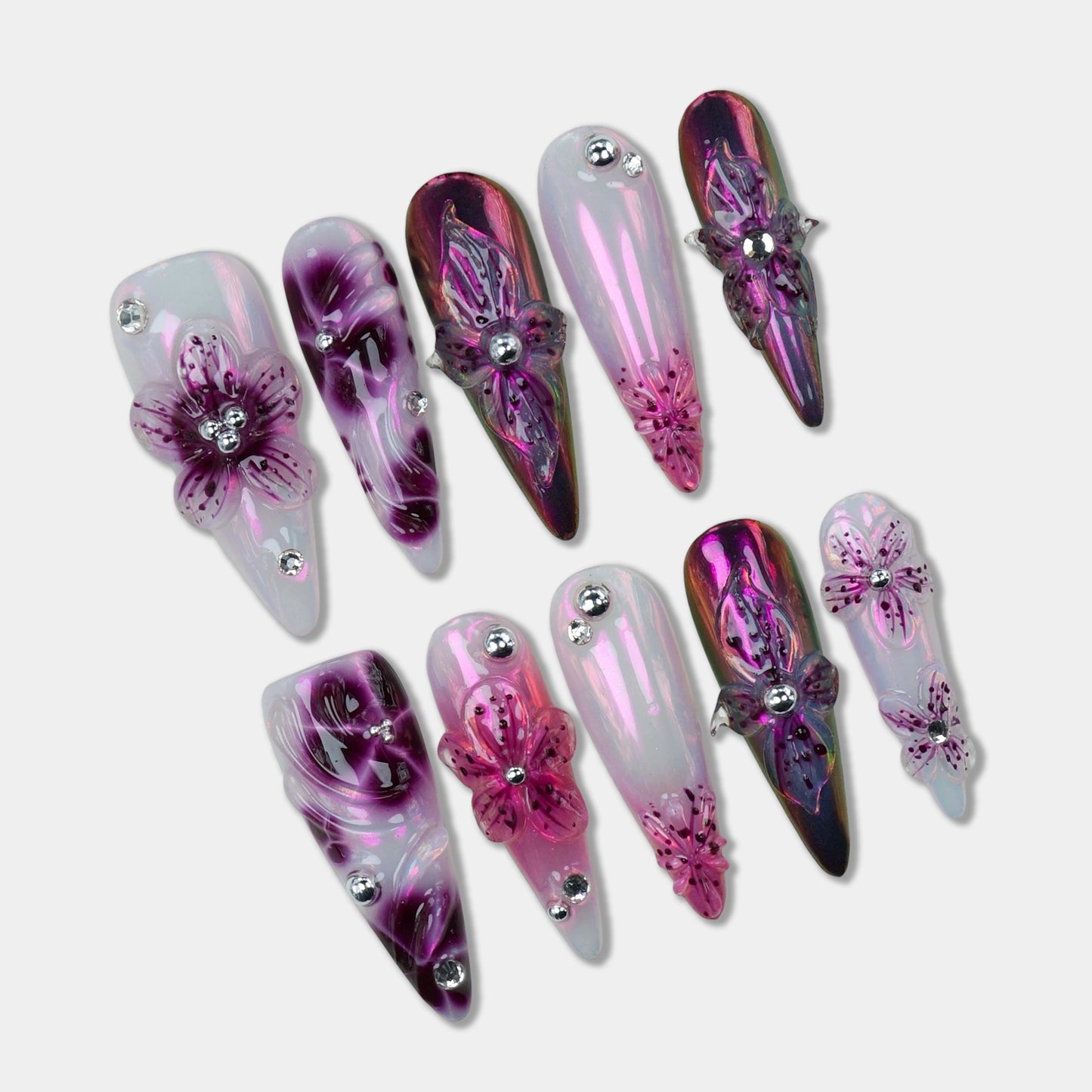 Glamorous flower design nails with iridescent chrome finishes and 3D purple blossoms accented by silver studs