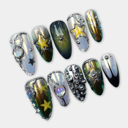 Holographic chrome press-on nails with metallic green-gold shifts, 3D star charms, silver beads, and gem accents.
