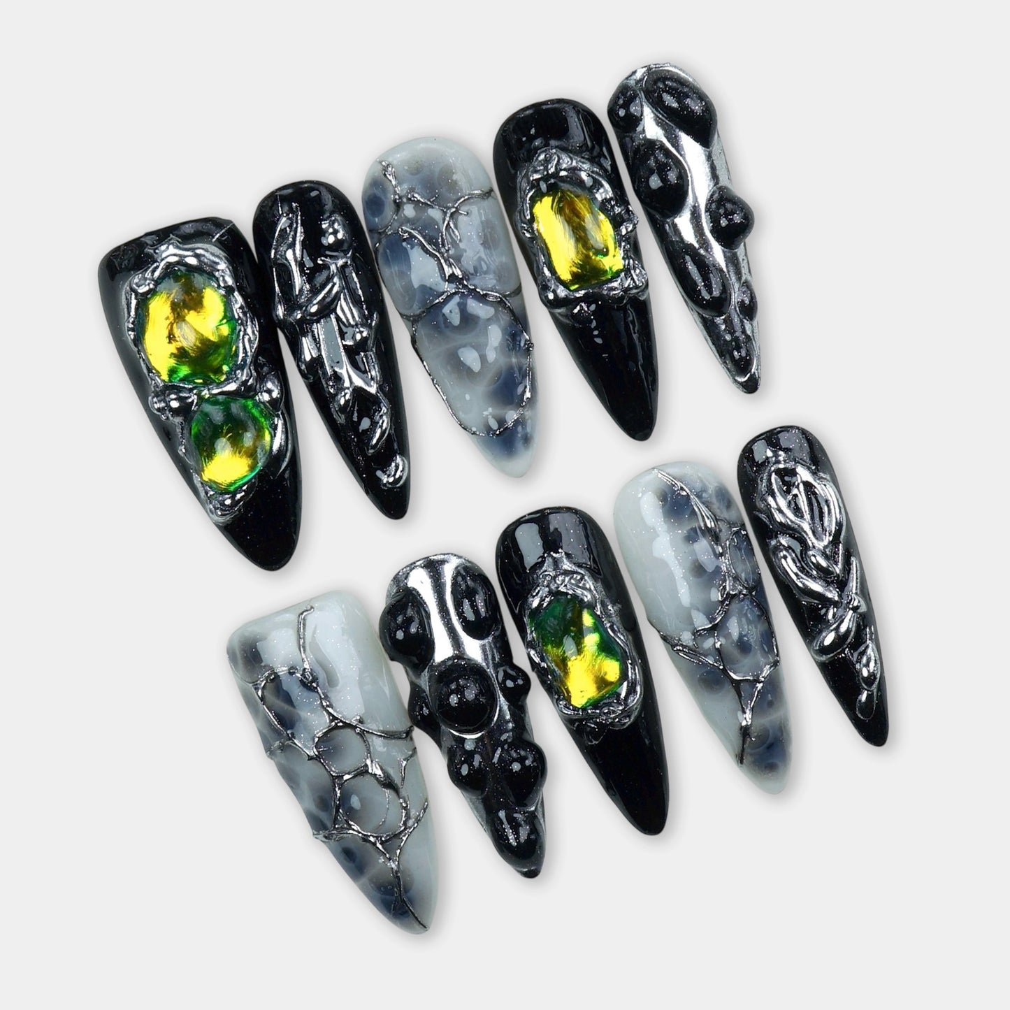 Black and smoky translucent press-on nails featuring chrome webbing, iridescent yellow-green gem accents, and 3D droplet textures.