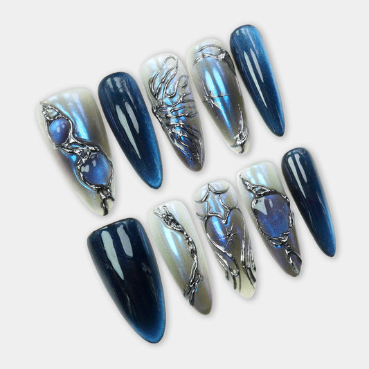 Press-on nails featuring deep blue cat-eye shimmer, metallic chrome details, and sculpted black frame accents by Donailsart