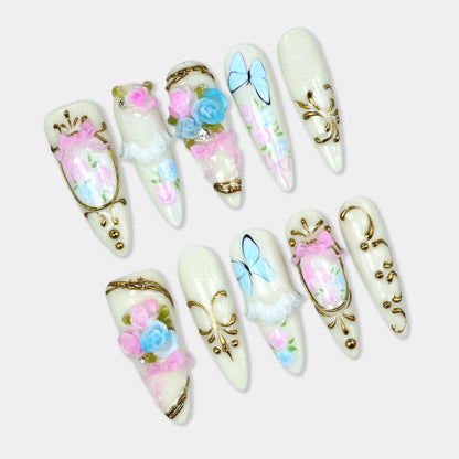 Birthday nails featuring pastel roses, blue butterflies, and gold ornate frames on a cream base by Donailsart