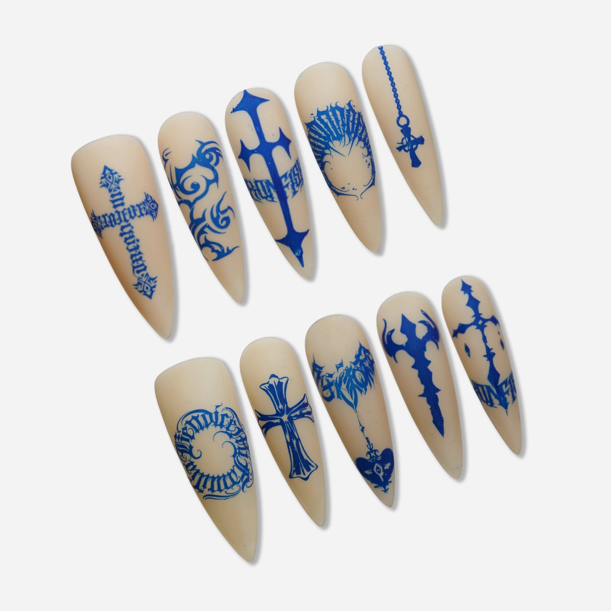 Blue Heresy press-on nail set by Donailsart – muted nude nails with sharp cobalt blue cross symbols, distorted typography, and tattoo-inspired graphic markings