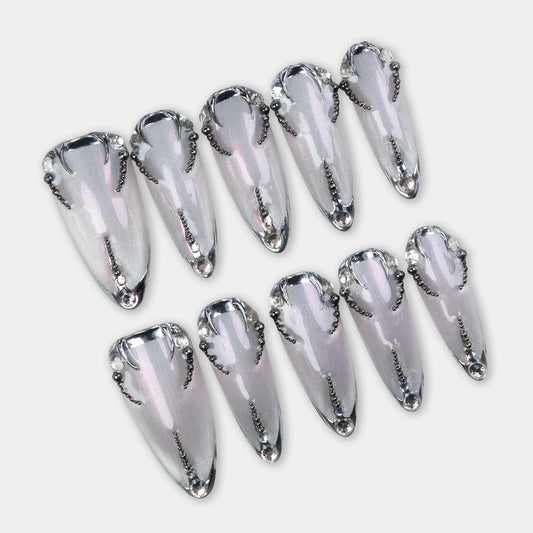 Shimmery silver press-on nails outlined with black chrome details and tiny beaded chains forming a symmetrical design.