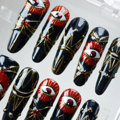 Eye-catching press-on nails with red-and-gold mystical eye art and luxurious metallic accents, handmade by Donailsart