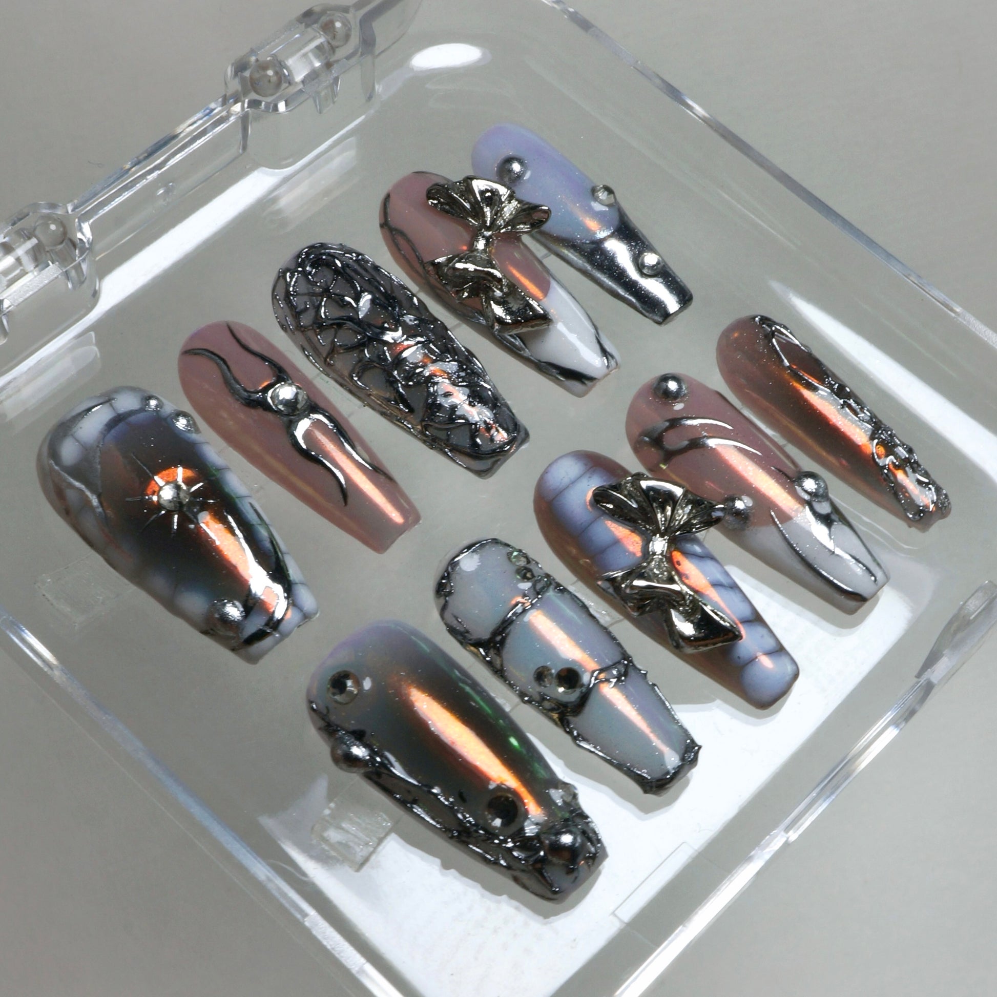 Chrome-effect press-on nails with gradient shimmer and silver 3D accents, a statement design by Donailsart.