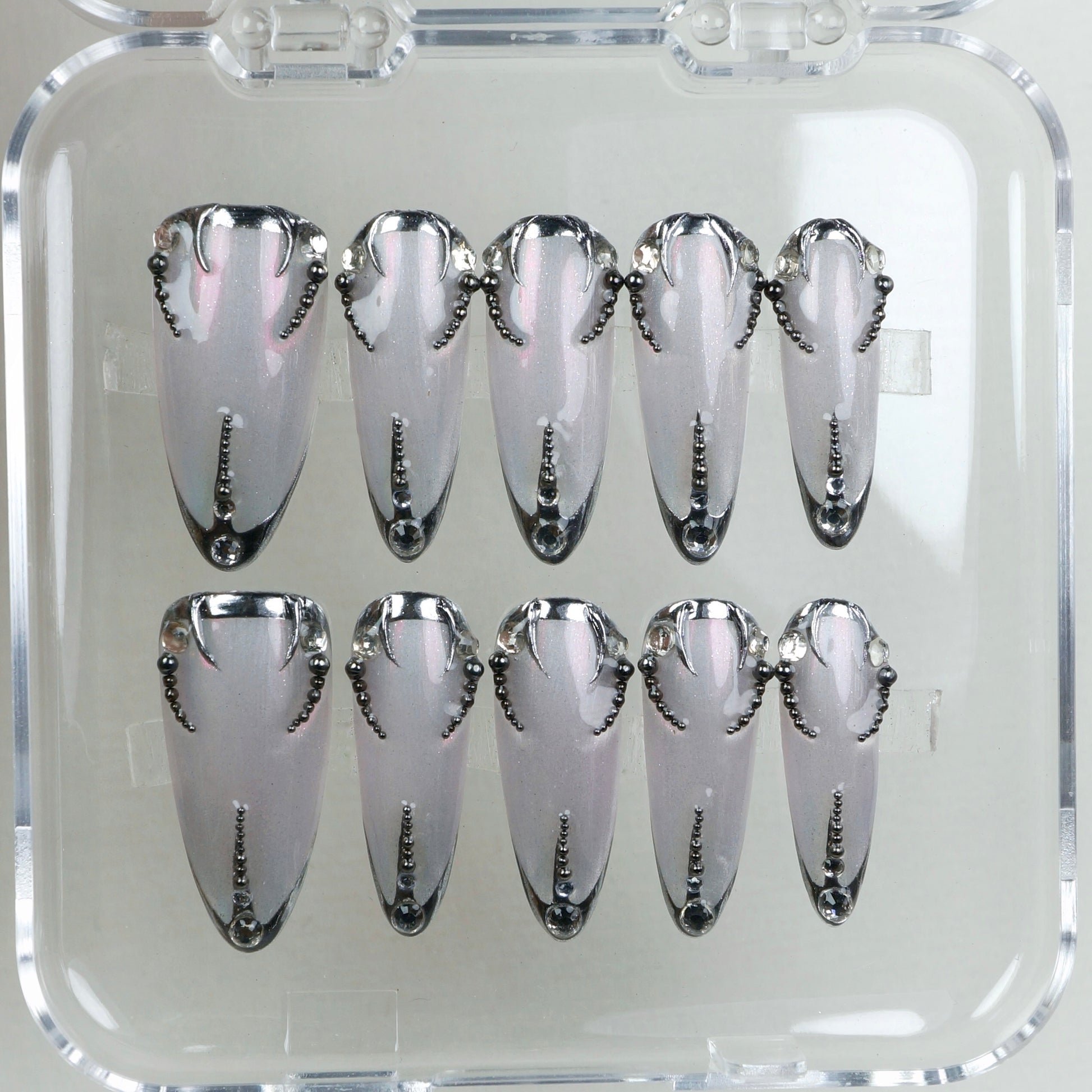 Pearl-silver press-on nails with sculpted black chrome tips and a dotted spine – classy with a dark twist.