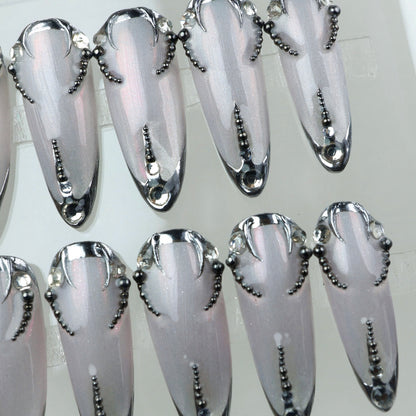 Sharp and sleek, these metallic press-on nails feature dark chrome edges and beadwork like a digital lace tattoo.