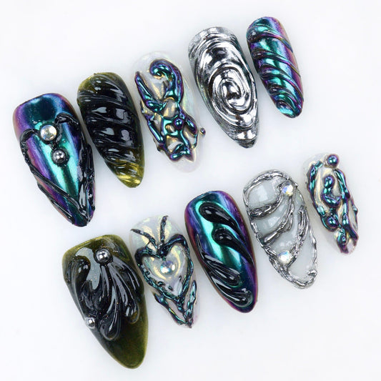 Glossy chrome press-on nails in dark iridescent tones with sculpted 3D textures, abstract swirls, and metallic details.