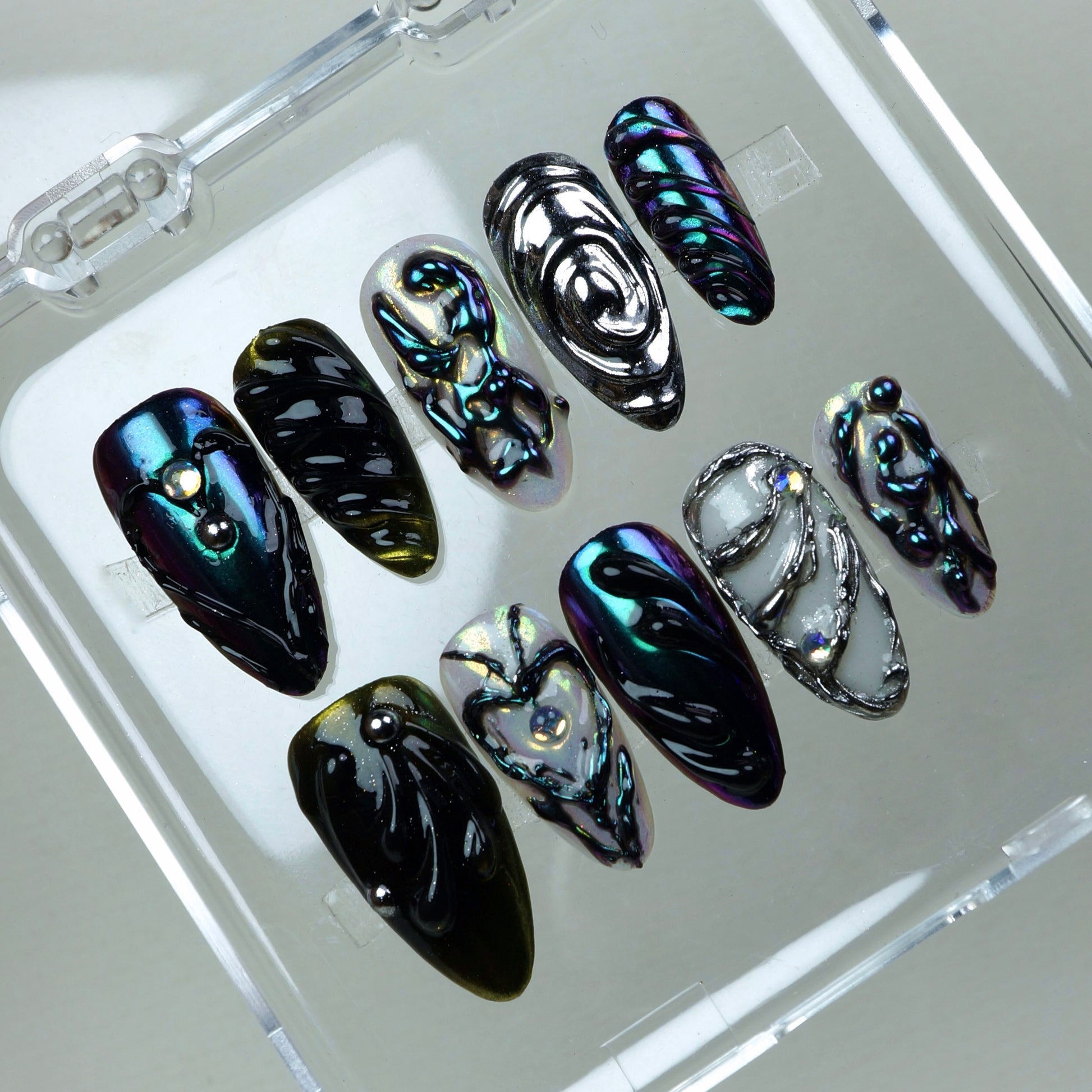 Galactic-inspired press-on nails featuring multichrome finishes, jelly-like swirls, and futuristic silver accents.