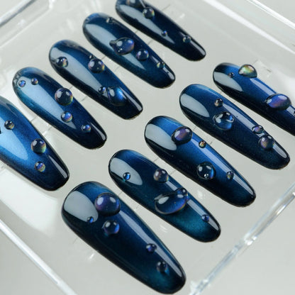 Elegant navy cat eye gel nails featuring depth-enhancing shimmer and glossy bubble-like droplets