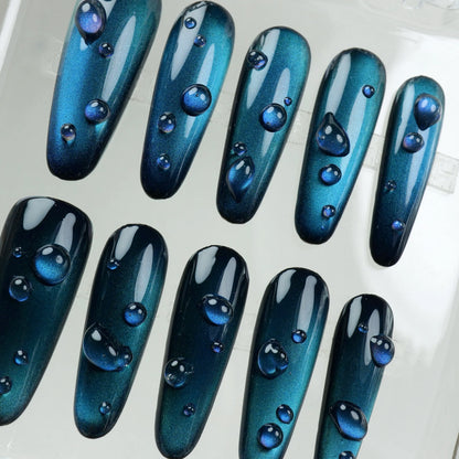 Minimalist cat eye gel nails in deep blue with a magnetic shift and transparent 3D water drops