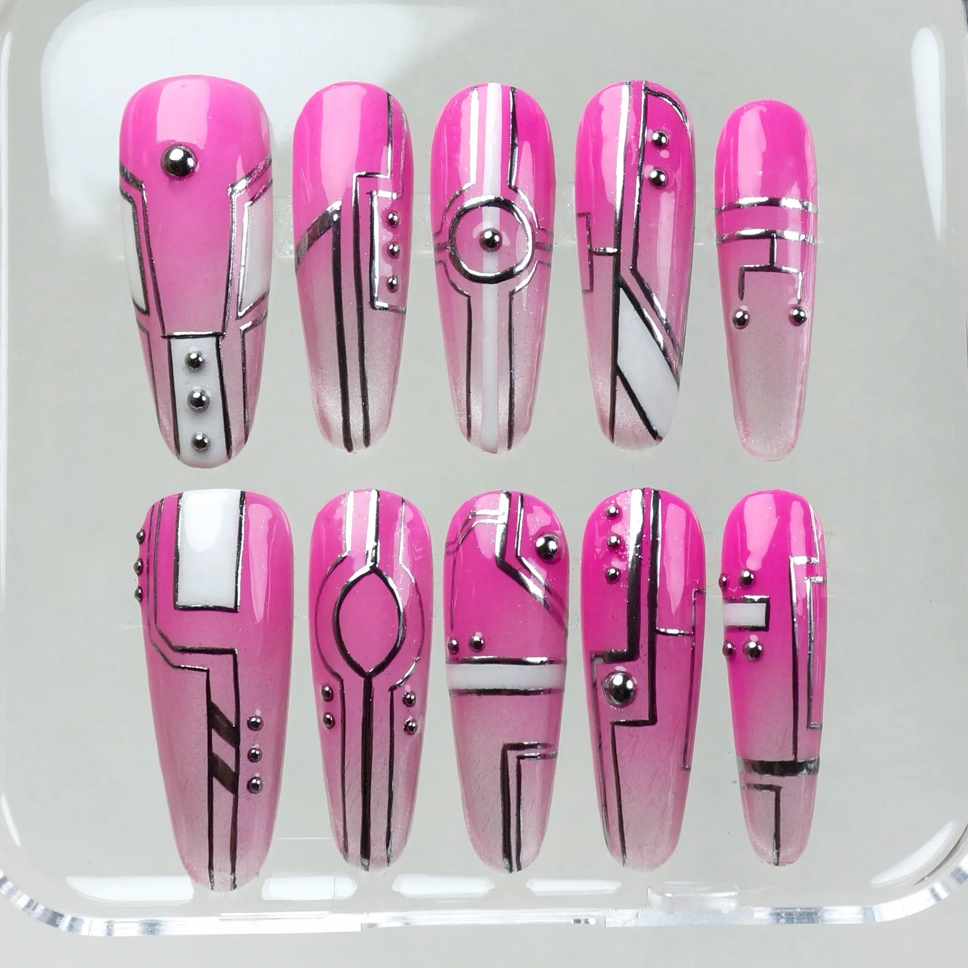 Pink press-on nails with chrome accents, cyberpunk shapes, and metallic dot embellishments