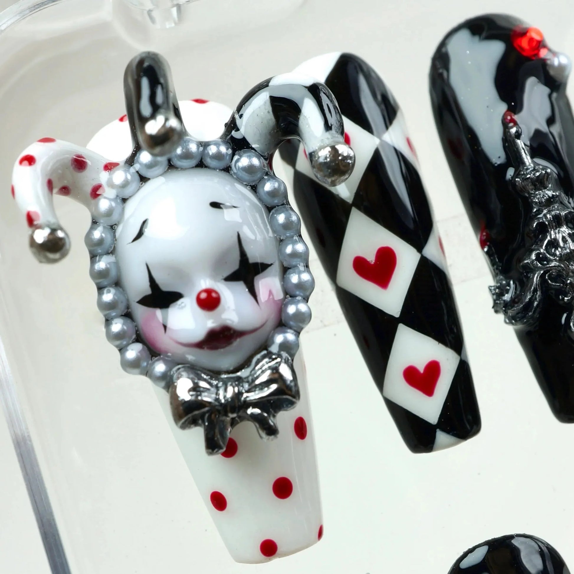 High-drama press-on nails with checkerboard patterns, pearls, and sculpted metal accents, designed by Donailsart.