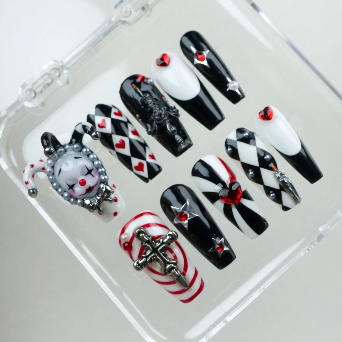 Bold black, white, and red press-on nails featuring jester motifs, gothic details, and heart embellishments from Donailsart.