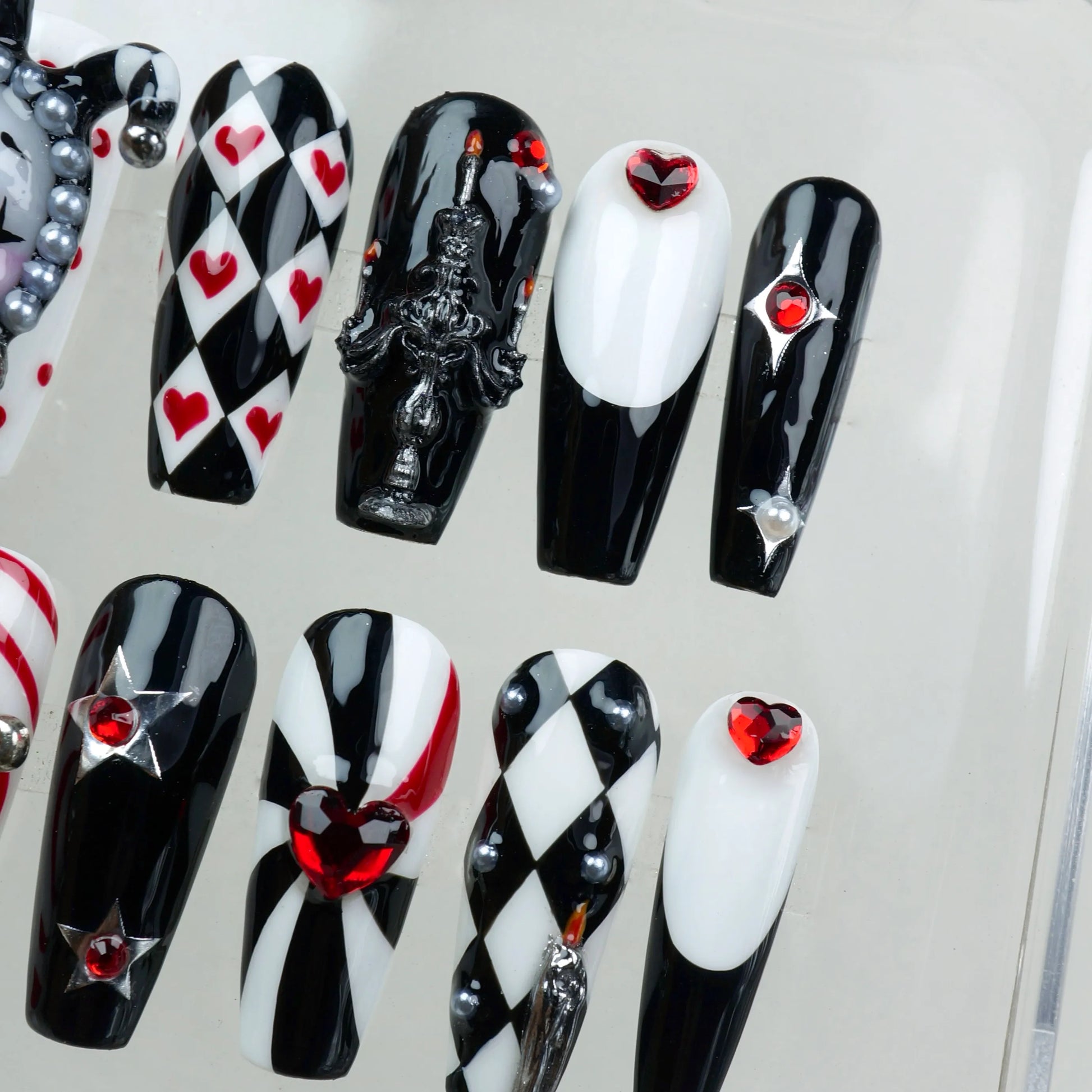Bold black, white, and red press-on nails featuring jester motifs, gothic details, and heart embellishments from Donailsart.