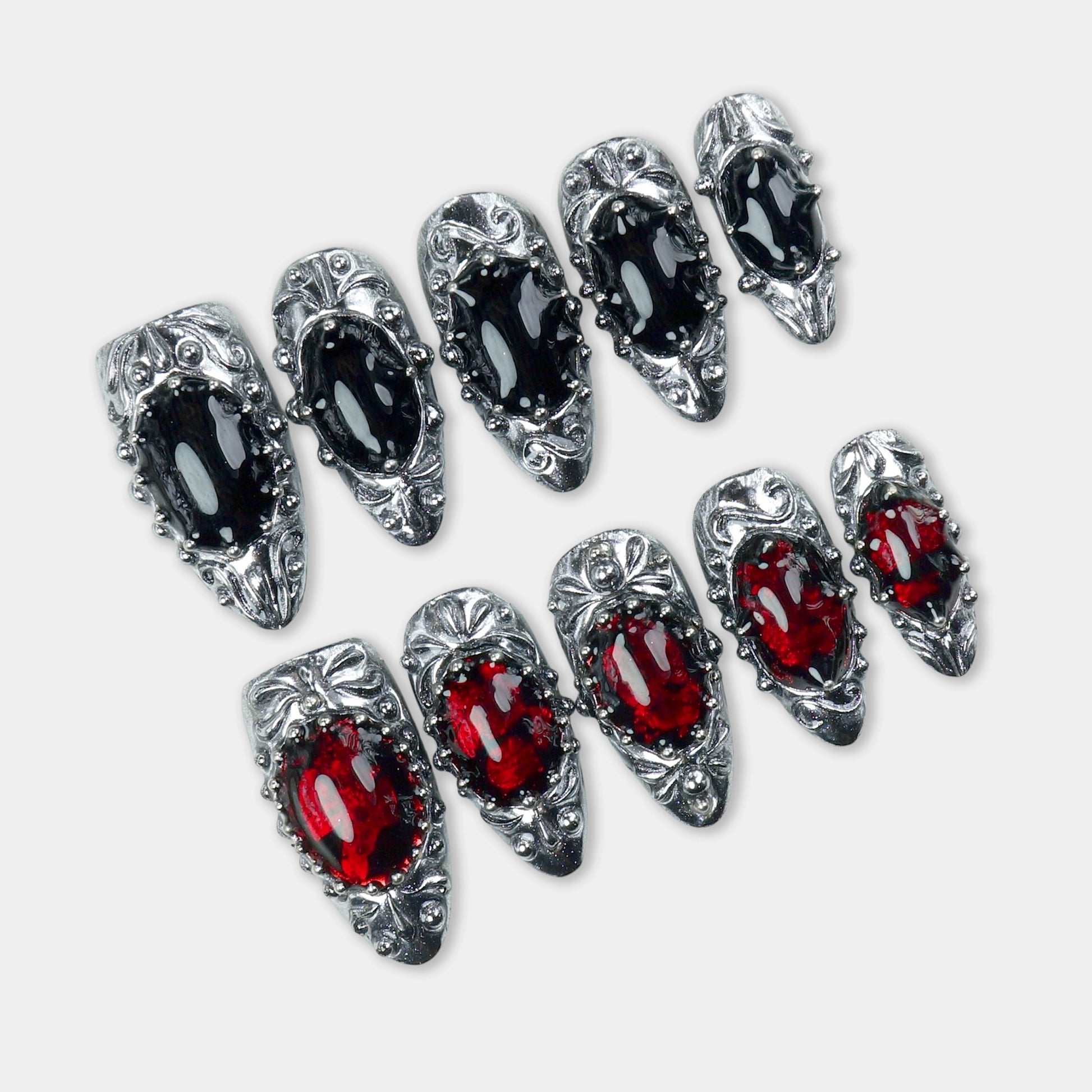 Press-on nails with gothic silver frames, black and red gem-like centers, and a medieval-inspired finish by Donailsart