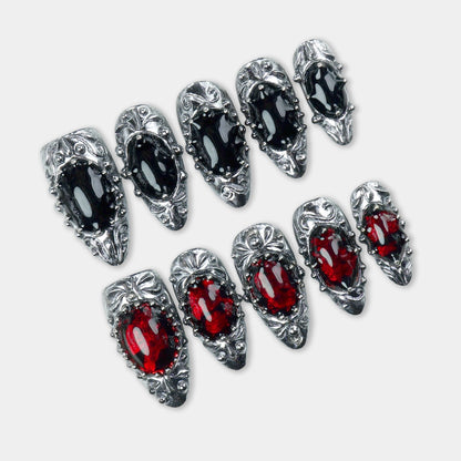 Press-on nails with gothic silver frames, black and red gem-like centers, and a medieval-inspired finish by Donailsart