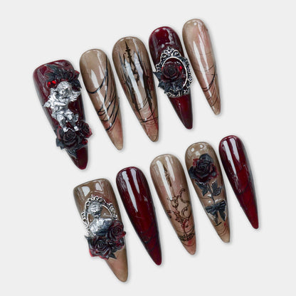 Gothic nails in deep wine and smoky nude tones with black rose art, metallic angels, and candle motifs – by Donailsart.