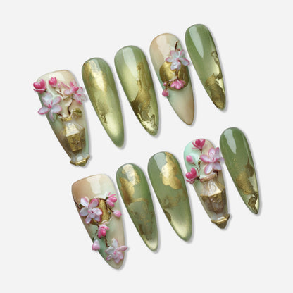 Garden Reverie press-on nail set by Donailsart – soft jade green nails with flowing gold accents, sculpted sakura blossom flowers, and ornamental vase detail