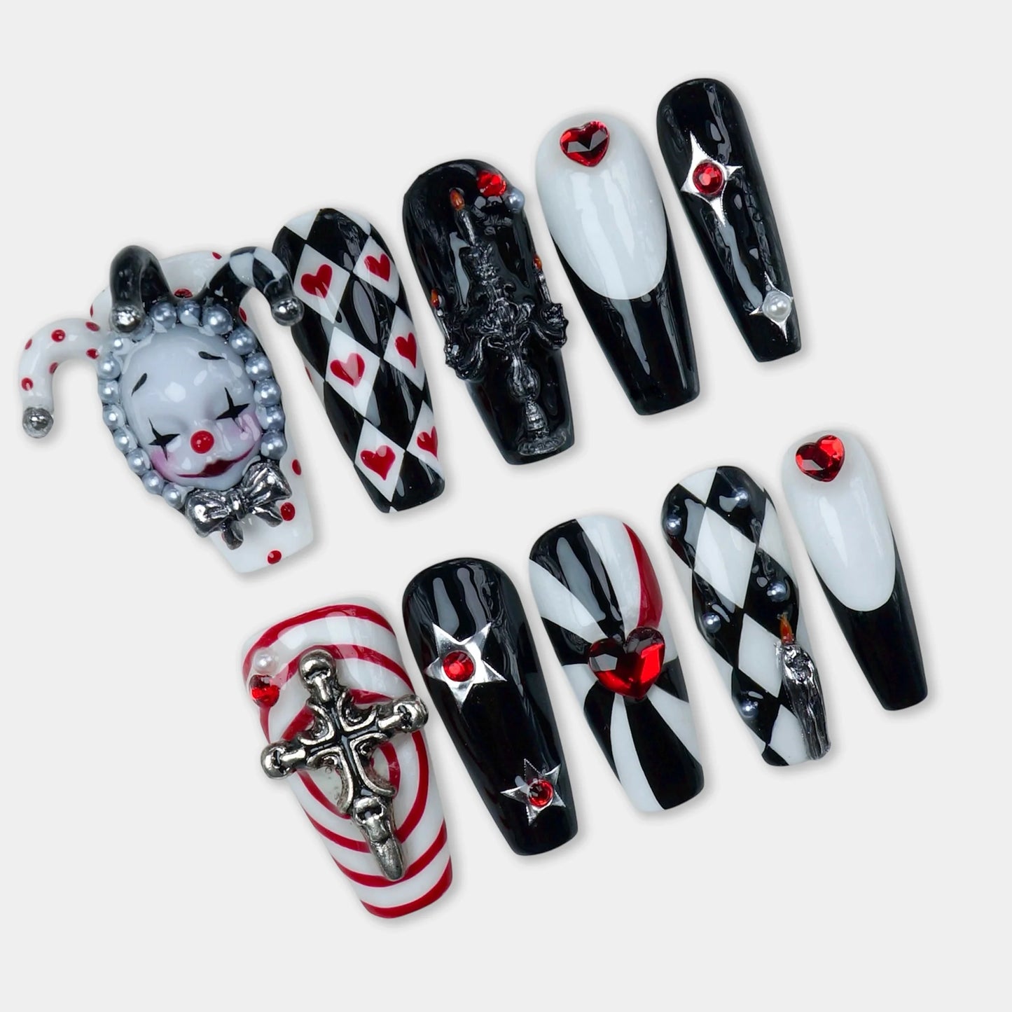 Harlequin-inspired press-on nails with red hearts, stripes, and a 3D clown face – handcrafted by Donailsart.