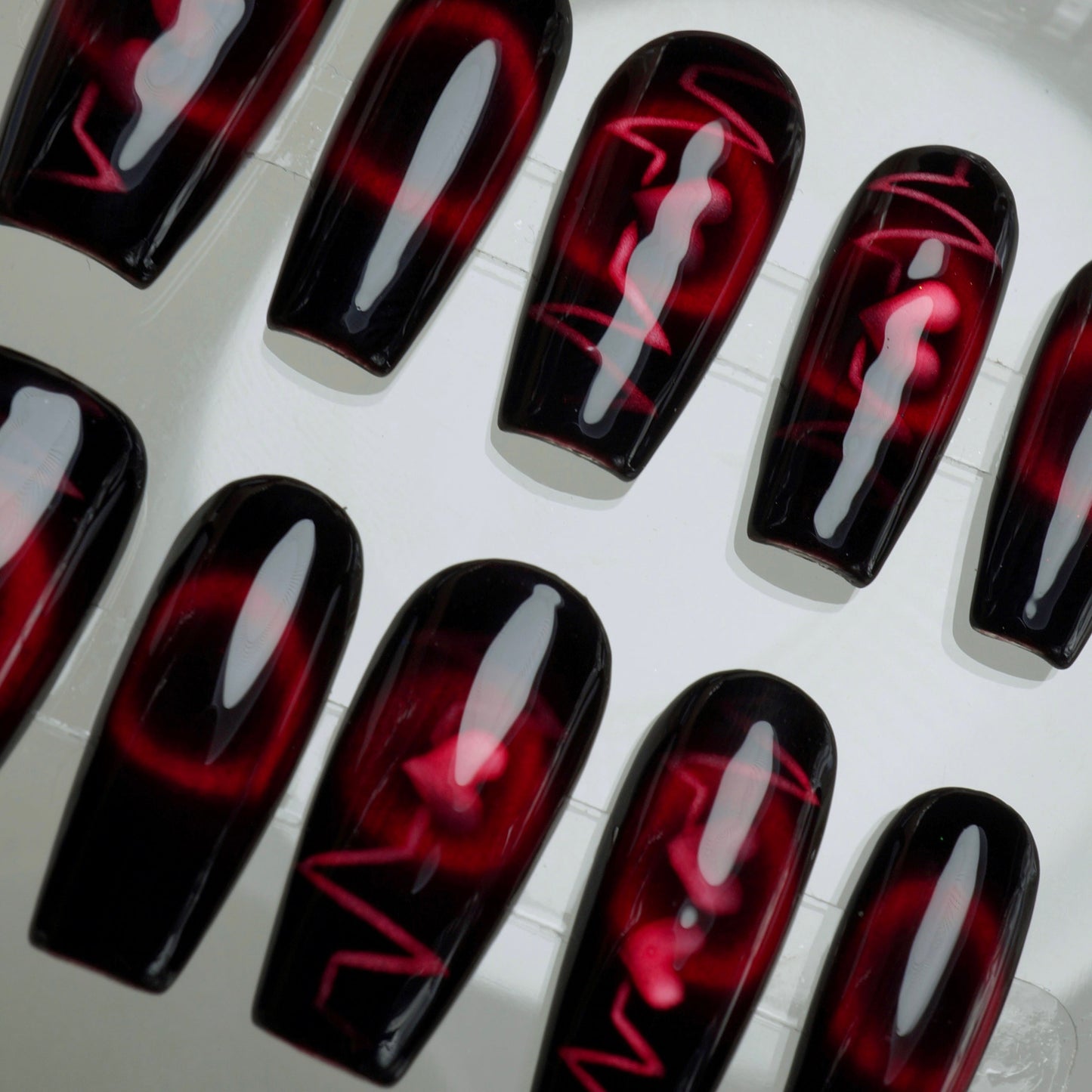 Black and red nail art designs on a white surface