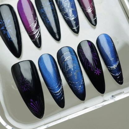 Holiday press-on nail set with dark cat-eye gradient, metallic blue tones, and firework motifs.