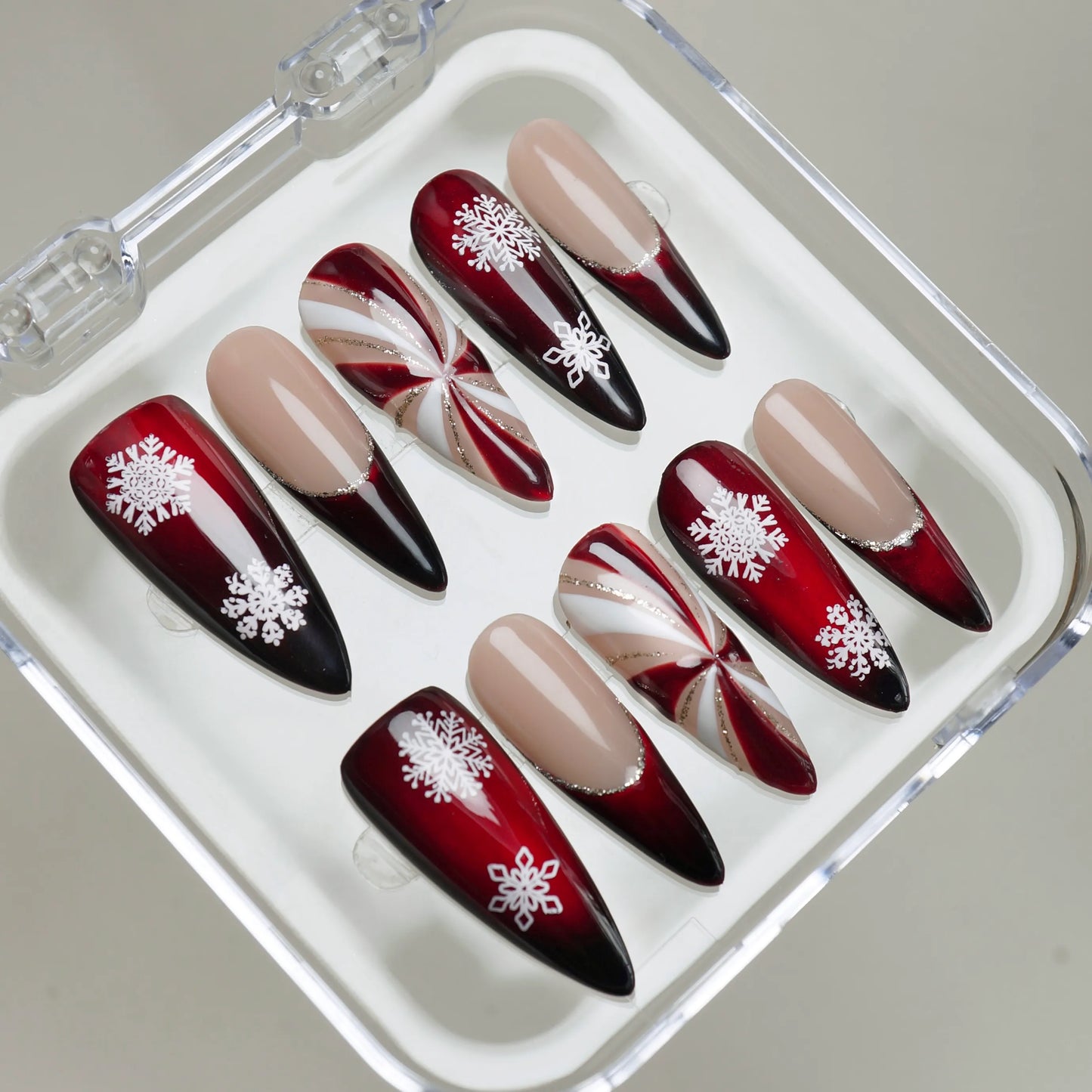 Glossy red gradient Christmas nails featuring white snowflakes and metallic swirl patterns Donailsart