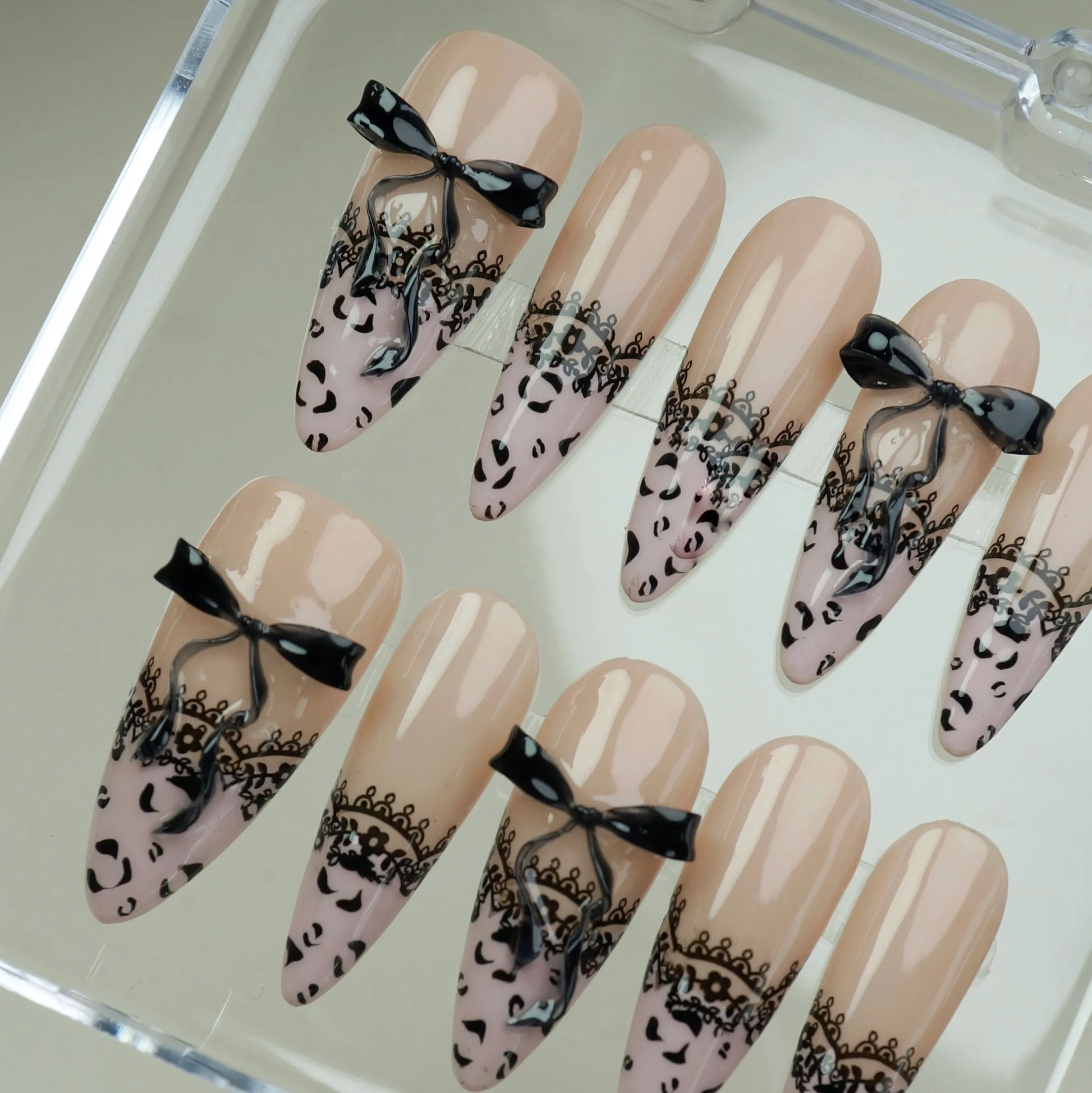 Noir Étreinte close-up detail showing black lace overlay and sculpted satin bow on a glossy nude nail – Donailsart