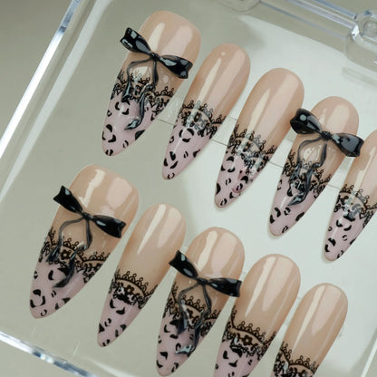 Noir Étreinte close-up detail showing black lace overlay and sculpted satin bow on a glossy nude nail – Donailsart