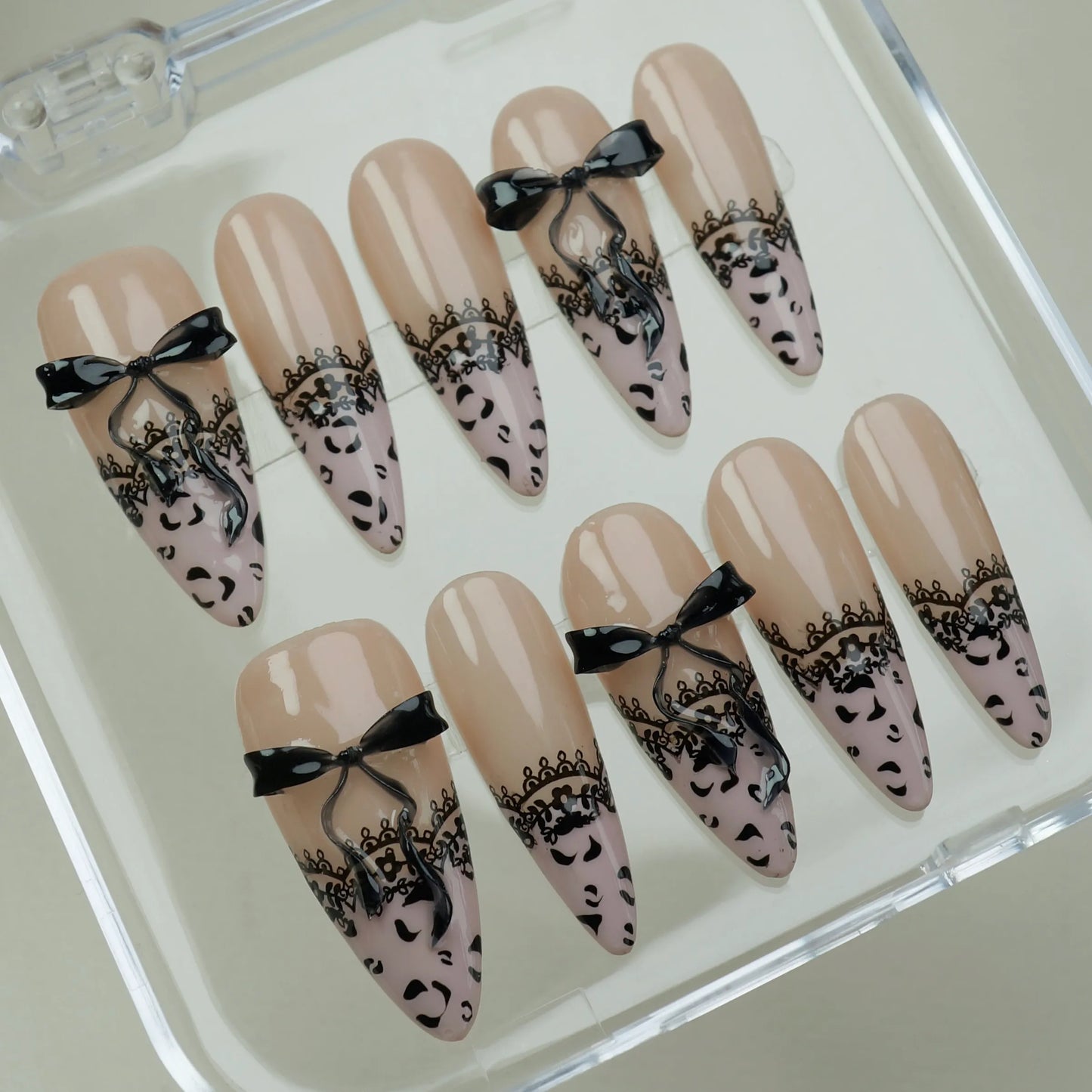 Noir Étreinte press-on nails on display showing the full nude and black lace bow nail art collection – Donailsart