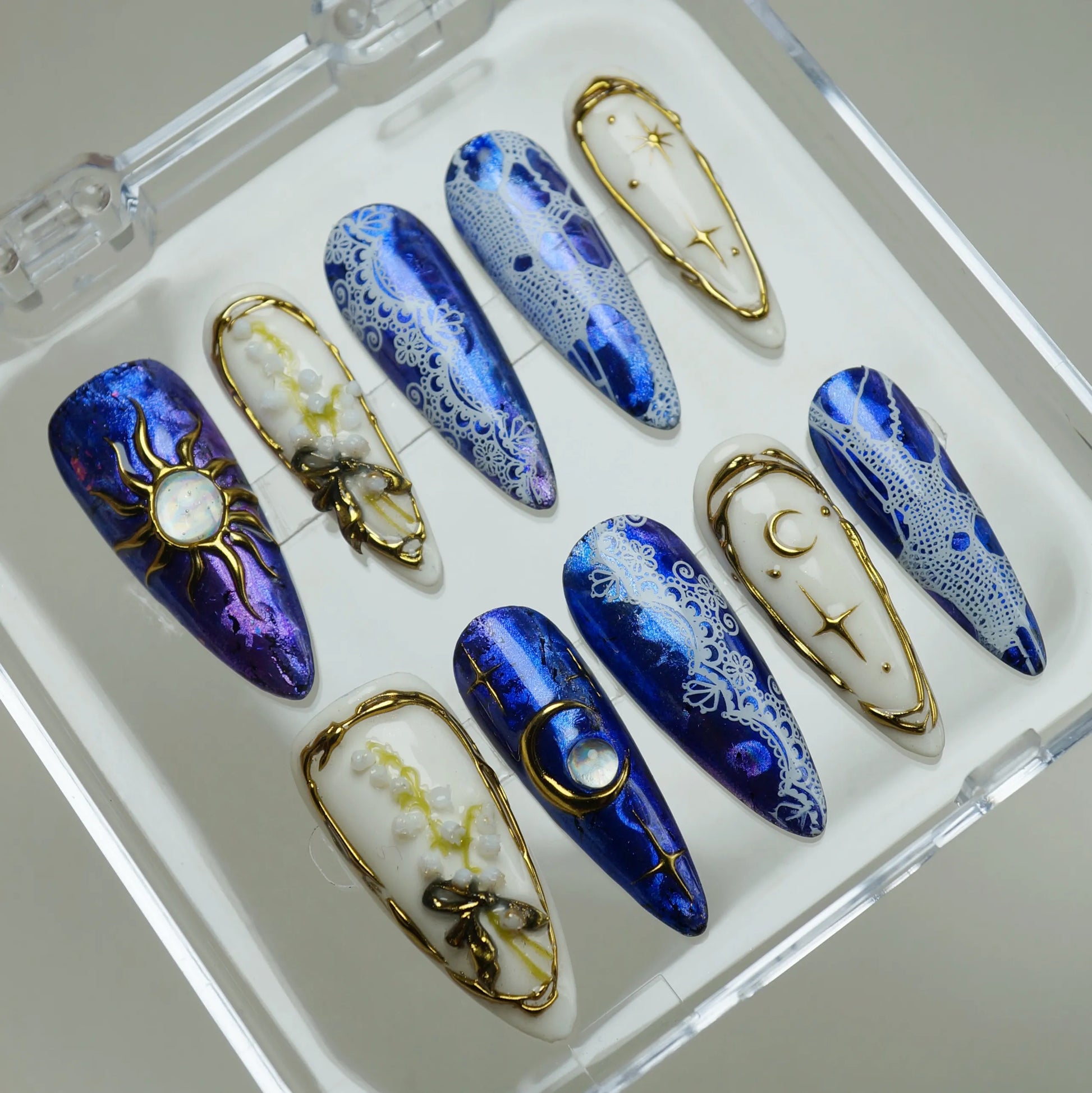 Celestine Sovereign press-on nails on display showing the full cobalt chrome and gold celestial lace nail art collection – Donailsart