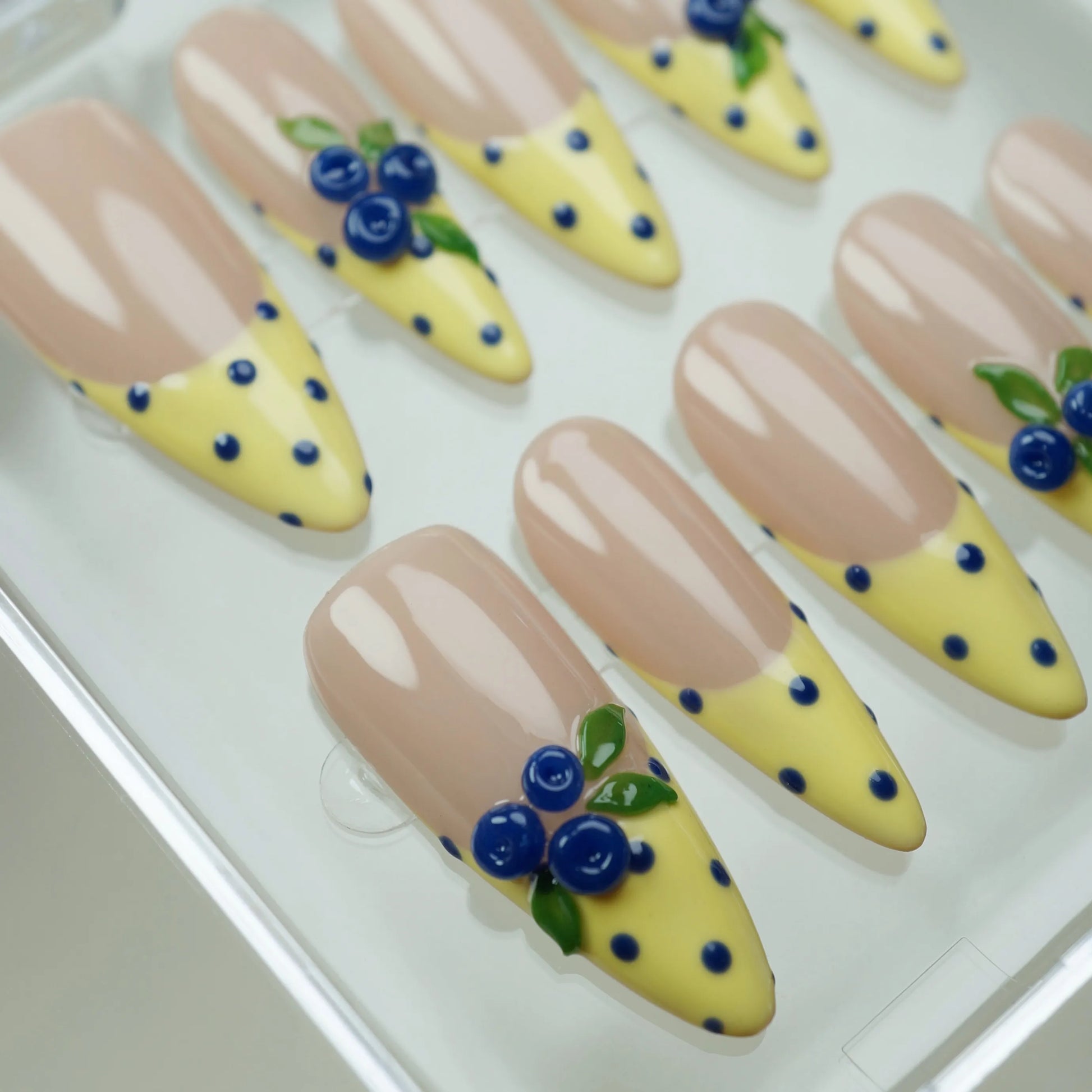 Solar Berries press-on nail set product view with cheerful yellow French tip, blue polka dot, and berry nail art by Donailsart