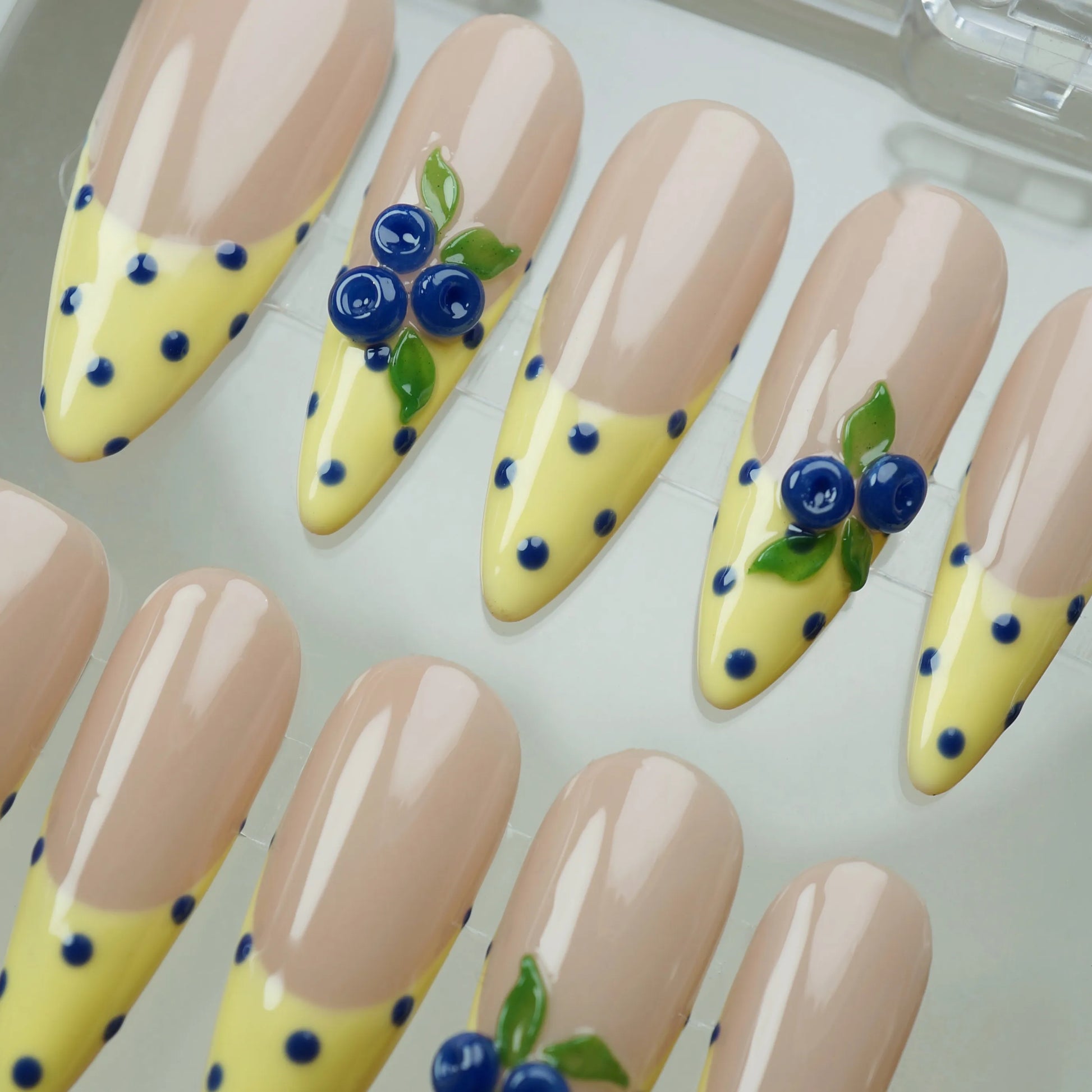 Solar Berries close-up detail showing hand-sculpted berry and leaf accents with blue polka dots on a yellow French tip nail – Donailsart