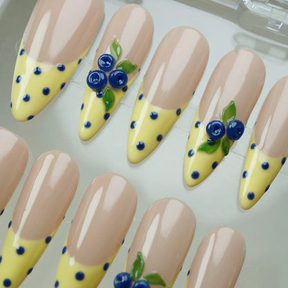 Solar Berries close-up detail showing hand-sculpted berry and leaf accents with blue polka dots on a yellow French tip nail – Donailsart